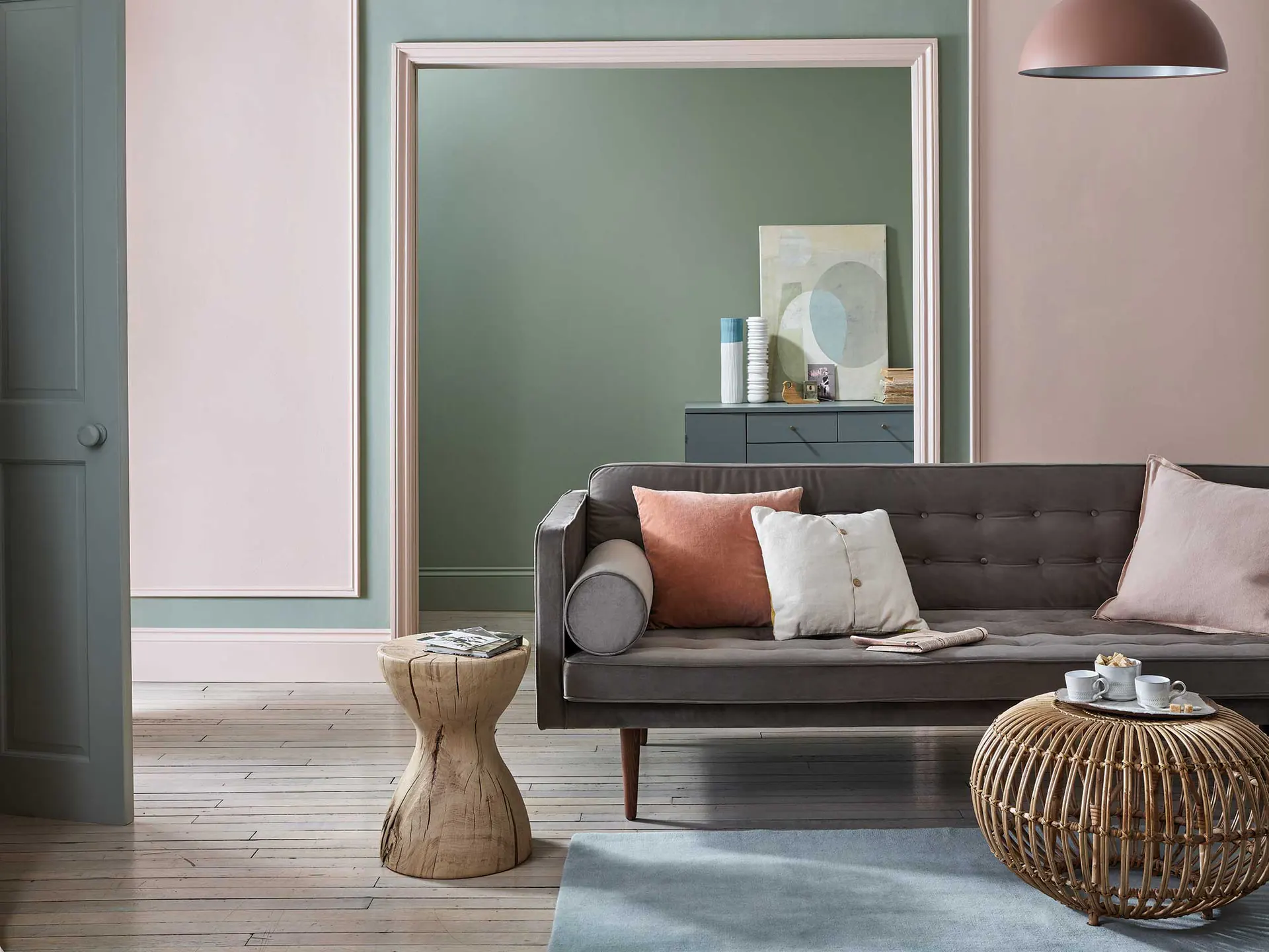 Salon en enfilade aux murs Lichen et Sulking Room Pink de Farrow & Ball, canapé gris et tables en rotin